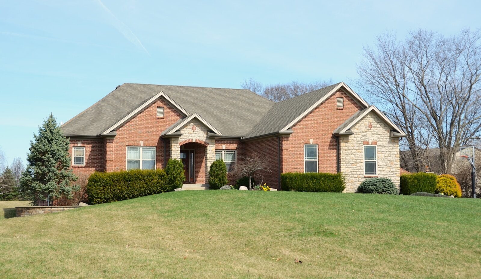 A large brick house with a manicured lawn.