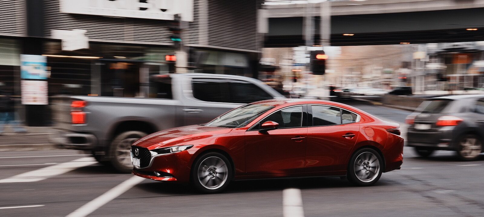 Red car driving through a city street.